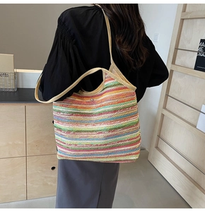 Detail of colorful striped woven tote bag with beige straps on a model in a natural room