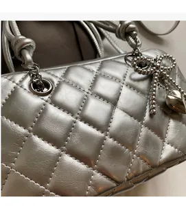Detail of silver quilted crossbody bag with beaded bow and heart metallic charms