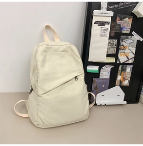 Close-up of minimalist off-white canvas backpack featuring multi-pocket design and natural texture