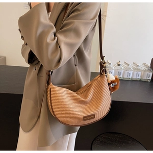 Detail of light brown woven crossbody bag with leather trim and plush charm accessory