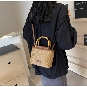 Detail of straw bucket bag featuring hand-crafted bamboo handles and woven texture