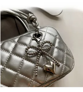Close-up of silver quilted crossbody bag featuring a metallic heart and bow charm