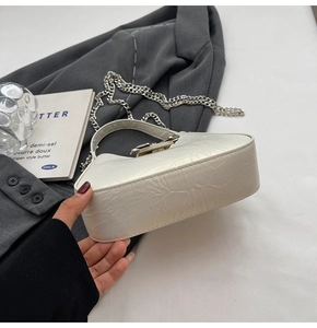 Détail du sac à main en cuir plissé blanc avec bandoulière chaîne argentée et fermoir métal