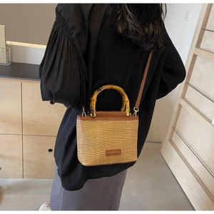 Detailed back view of a straw bucket bag with bamboo handles and adjustable shoulder strap
