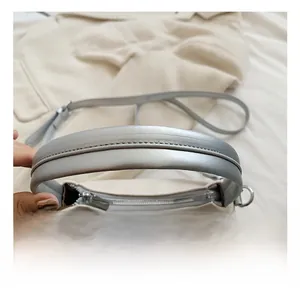 Detail showing comfortable silver handle of the cream crossbody bag with top metal zipper