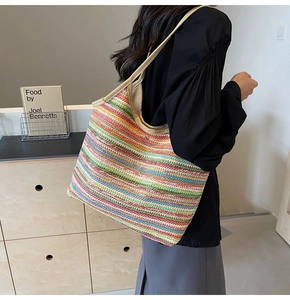 Detail of colorful striped woven tote bag with wooden handles on a shoulder