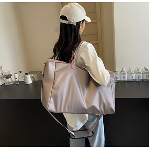 Détail d'un grand sac de voyage en nylon champagne avec anses roses dans un café