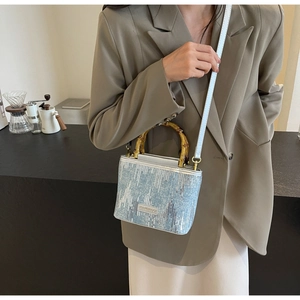 Detail of light blue sequin bucket bag featuring a natural bamboo handle and silver logo