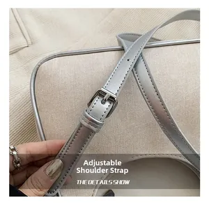 Detail view of adjustable silver shoulder strap with metal buckle on beige canvas bag