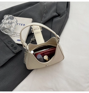 Vue de dessus de l'intérieur du sac à bandoulière crème avec chaîne et objets quotidiens