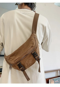 Detail of brown canvas crossbody bag featuring adjustable strap and multi-pocket design