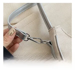 Close-up of premium silver metal hook and leather trim on a canvas shoulder bag