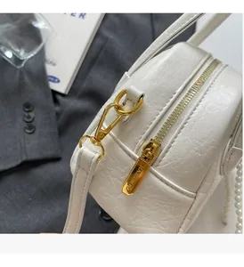 Détail du sac blanc texturé avec fermeture éclair dorée et chaîne en perles chic