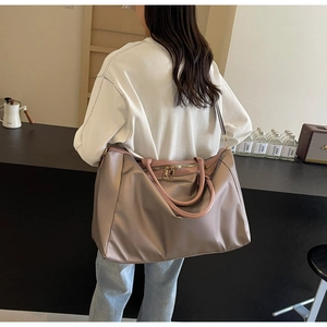 Vue détaillée du grand sac de voyage rose tendre avec doubles poignées et bandoulière