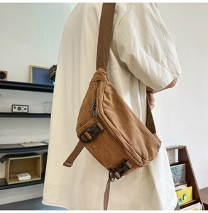 Close-up of brown canvas crossbody bag with multi-layer zippers and adjustable strap