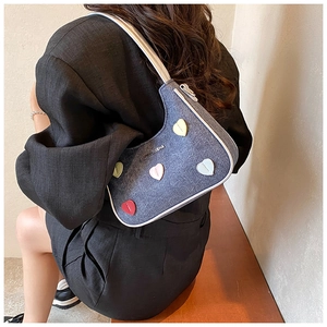 Detail of blue denim hobo bag with colorful heart patches and white contrast piping