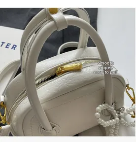 Détail de la fermeture éclair dorée et texture sur sac coquillage en cuir blanc