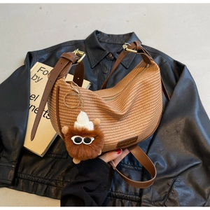 Detail of brown woven crescent bag with leather strap and plush monster pendant charm
