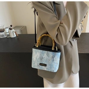 Detail of light blue sequined bucket bag with authentic bamboo handle and brand logo