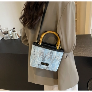 Close-up of blue sequined bucket bag with carbonized bamboo handle and gold hardware