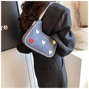 Detail of blue denim shoulder bag with colorful 3D heart motifs and white leather strap