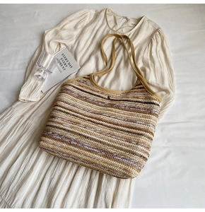 Detailed top view of striped straw tote bag with snap button on a beige summer dress