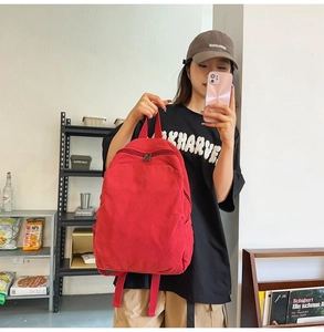 Detail view of bright red canvas backpack with metal zippers and spacious pockets