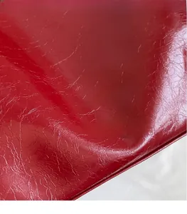 Detail of red glossy leather tote bag with embossed logo and wrinkled texture