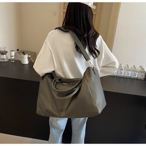 Détail d'un grand sac de voyage gris foncé avec fermetures éclair dorées et poignées