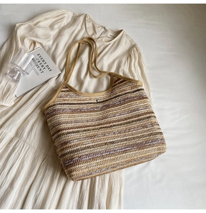 Detail of striped woven tote bag with metallic snap closure and reinforced handles
