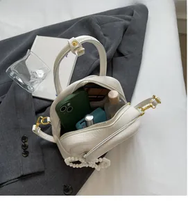 Intérieur spacieux du sac à main blanc en forme de coquillage avec chaîne de perles