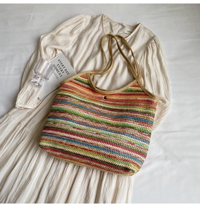 Close-up of rainbow woven tote bag on white dress showing texture and metal buckle