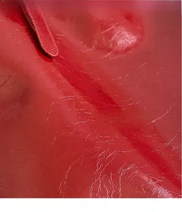 Close-up of bright red tote bag with a shiny wrinkled texture and glossy leather finish