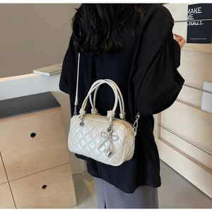 Detail of cream quilted crossbody bag with silver bow charm and detachable strap