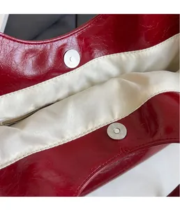 Detail of red patent leather tote with silver magnetic buckles and silk interior