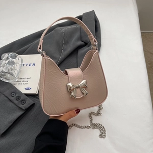 Sac hobo rose avec n&oelig;ud métallique et bandoulière chaîne sur une veste de costume grise