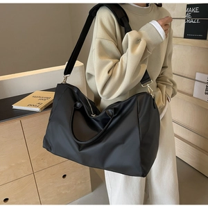Détail du grand sac de voyage noir montrant le tissu durable et les finitions dorées
