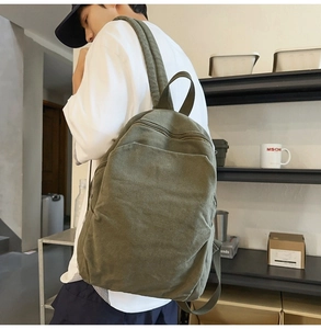 Detailed view of durable army green canvas backpack with wide straps and metal zippers