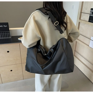 Détail d'un grand sac de voyage noir avec ferrures dorées et bandoulière réglable