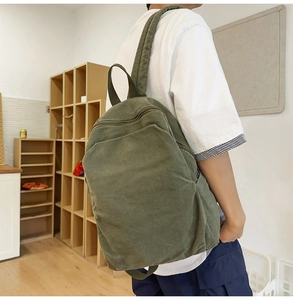 Side view of olive green canvas backpack with adjustable wide straps and side pocket detail