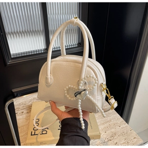 Détail du sac blanc plissé avec nɶud en perles et pendentif en forme de cœur