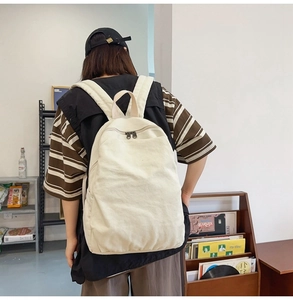 Detailed view of cream canvas backpack with wide straps in an artistic studio setting
