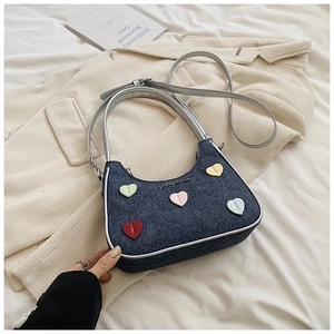 Close-up of denim shoulder bag with colorful heart patches and adjustable silver strap