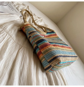 Detailed close-up of colorful striped woven straw tote bag with khaki webbing handles