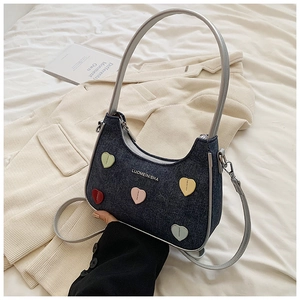 Detail of half-moon denim handbag with heart appliques on a beige corduroy coat