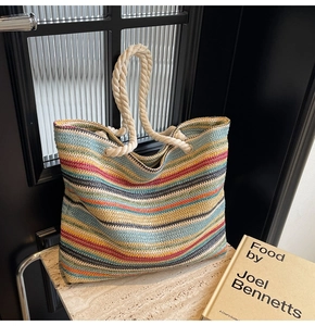 Détail du sac cabas tissé à rayures colorées avec anses en corde sur socle en pierre