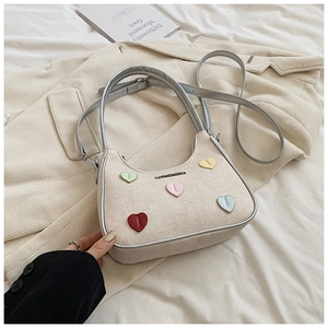 Detail of cream canvas handbag with colorful heart patches and silver metallic handles