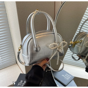 Vue détaillée du sac argenté avec nœud en perles et pendentif en forme de cœur