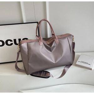 Détail macro du tissu imperméable brillant et des sangles roses sur le sac de voyage gris