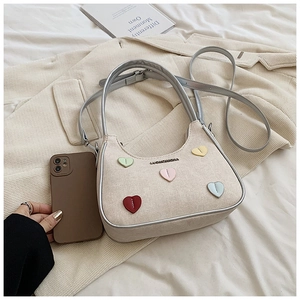 Detail of cream canvas bag featuring five colorful heart patches and adjustable strap